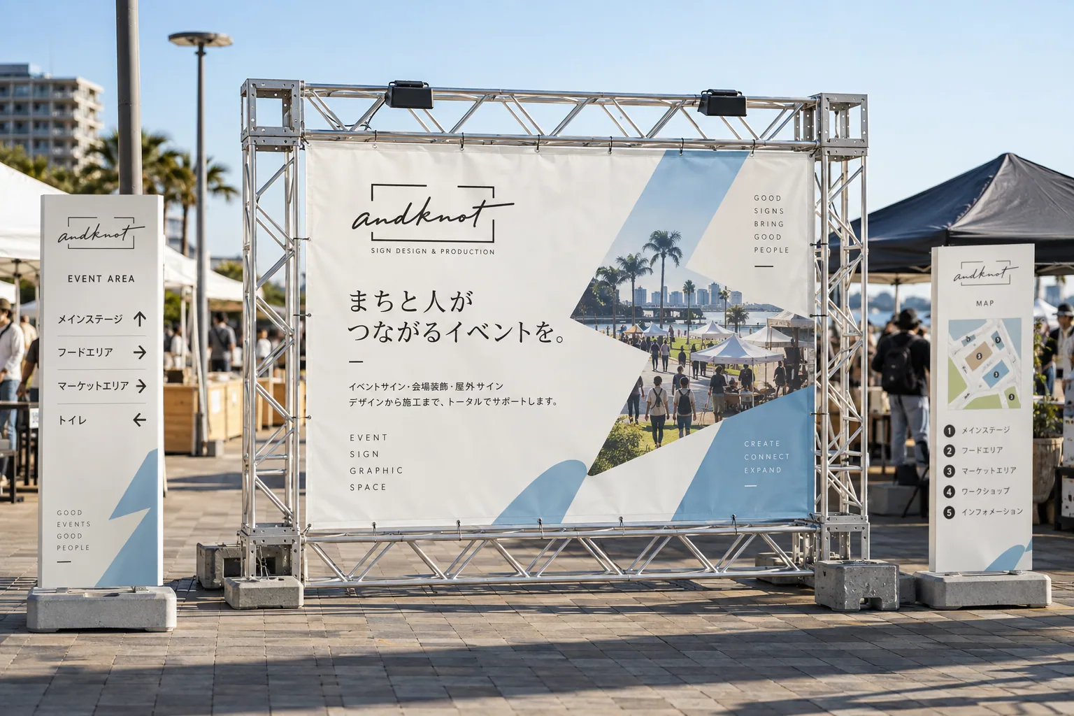 屋外イベント会場に設置されたand knotの大型バナーと案内サインのイメージ